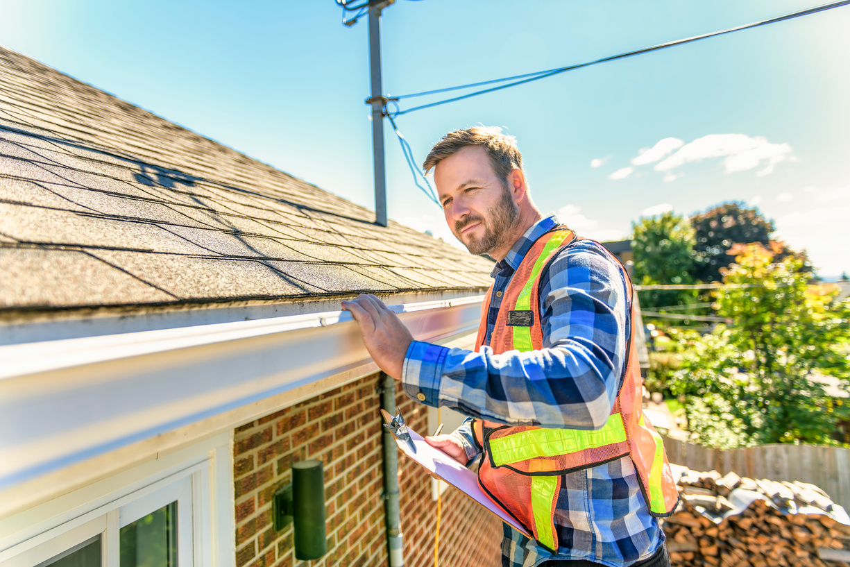 man standing on steps inspecting house roof